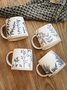 four coffee mugs sitting on top of a wooden table