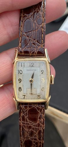 Offered for your consideration: Handsome Hamilton 10k gold filled Art Deco Tonneau shaped mechanical Men's wrist watch, c. 1940 - 1949. The dial is two-toned white & champagne, sub-dial @ 6'oclock, gold numerals & markers, original curved crystal,(has scratches) fancy lugs. In very good running order, surface wear consistent with age. It comes with a new leather strap. Signed Hamilton on the dial & Hamilton 10k Gold Filled on the back of the case. This would make a great Gift idea! Fast, Free US Luxury Timeless Watch Band With Solid Link Construction, Cheap Timeless Watch With Analog Display, Luxury Men's Formal Watch Accessories, Luxury Formal Men's Watch Accessories, Luxury Minimalist Formal Watches, Cheap Brown Watches For Gifts, Luxury Classic Chronometer Watch, Luxury Classic Watch With Analog Display, Luxury Polished Finish Adjustable Watch