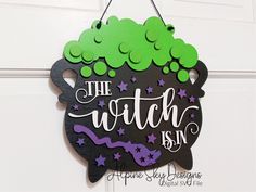 a sign that says the witch is in front of a door with green and purple decorations