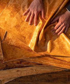 two hands on top of a large piece of yellow paper that has been folded over