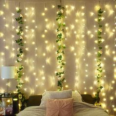 a bed with white lights hanging from it's sides and greenery on the headboard