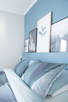 a bed with two pictures on the wall above it and blue walls in the background