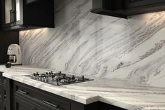 a kitchen with marble counter tops and black cabinets