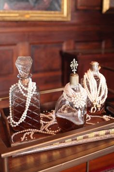 three glass bottles with pearls on them sitting on a table