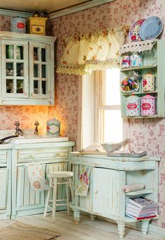 an old fashioned kitchen with pastel green cabinets and floral wallpaper on the walls