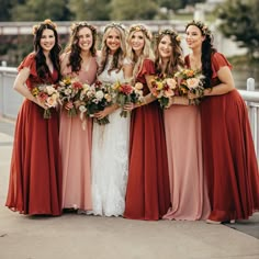 a group of women standing next to each other wearing dresses and holding bouquets in their hands