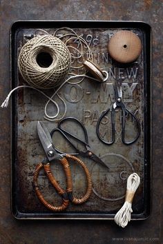 an assortment of crafting items displayed on a metal tray with scissors and twine