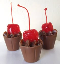 three chocolate cups with cherries on top