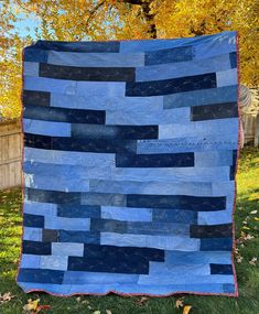 a blue and black quilt sitting on top of grass