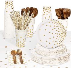 a table topped with white and gold polka dot paper cups filled with forks and spoons