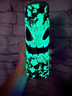 a hand holding a lit up cup with an alien face on it