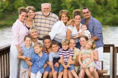 a group of people that are standing on a bridge near the water and smiling at the camera