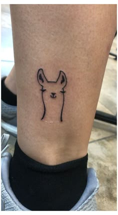 a small tattoo on the ankle of a woman's leg with a dog head