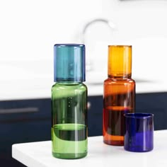 three different colored glass vases sitting on top of a counter