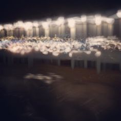 blurry photograph of tables and chairs in front of a wall with lights on it