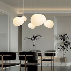 a modern dining room with black chairs and white globe lights hanging from the ceiling above