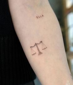 a lady with a tattoo on her arm that reads ella and the scale of justice