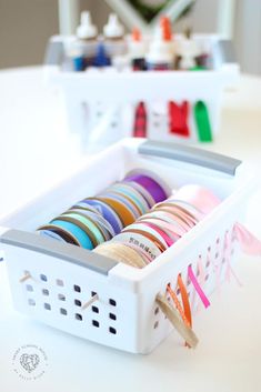 a white basket filled with lots of different colored ribbons