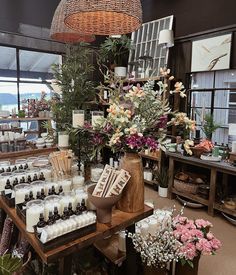 a table filled with lots of different types of bottles and candles next to flowers in vases