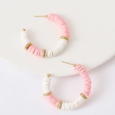 two pairs of pink and white hoop earrings on top of a white plate with gold accents