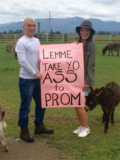 two people standing next to each other holding up a sign with animals in the background