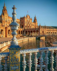 an ornate balcony railing overlooks the water in front of a large building and bridge