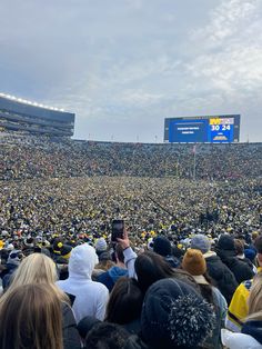 a large group of people at a football game in the stadium with one person holding up a cell phone