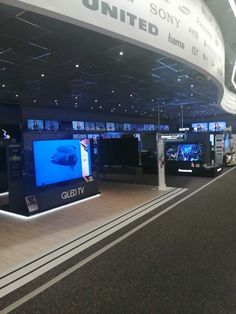 the interior of an airport with several televisions on display