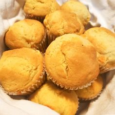 a bunch of muffins sitting on top of a white cloth in a basket