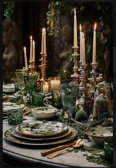 a table topped with lots of plates covered in green and white dishes next to candles