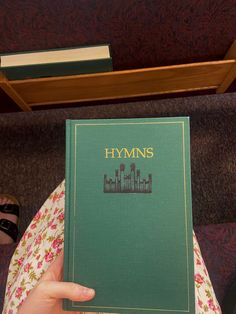 a person holding up a book in their hand with the words hyms on it