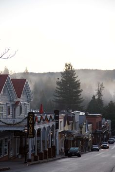 a street with cars parked on both sides and houses in the background, surrounded by fog