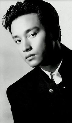 a black and white photo of a young man in a suit with a tie on