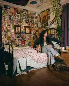 a woman sitting on top of a bed in a room with lots of wallpaper