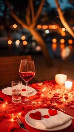 the table is set with candles, plates and wine glasses for valentine's day