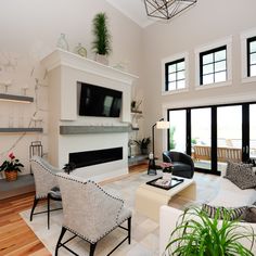 a living room with couches, chairs and a television mounted on the wall in it