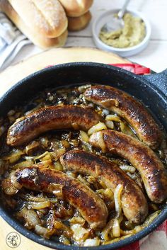 sausages and onions in a skillet with bread on the side