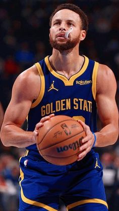 a man holding a basketball in his right hand and looking up at the ball with one eye open