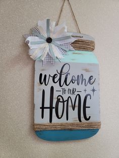 a welcome sign hanging from the side of a wall with a bow on it's head