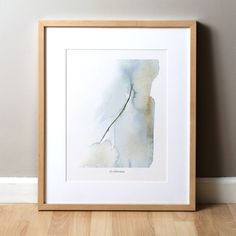 a watercolor painting of a plant in a wooden frame on the floor next to a wall