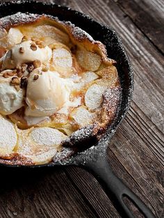 an iron skillet filled with dessert on top of a wooden table