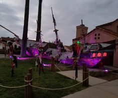 some people are standing in front of purple lights and pirate ships on display at night