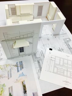 an architectural model is laying on top of some blueprints and papers with drawings