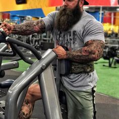 a man with a long beard and tattoos on his arm is using a treadmill