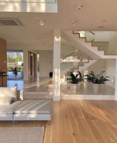 a living room filled with white furniture and wooden flooring next to a stair case