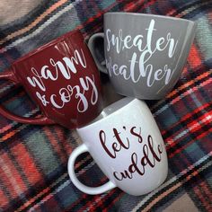 two coffee mugs sitting on top of a plaid blanket