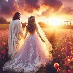 two people dressed in wedding gowns walking through a field at sunset with the sun behind them