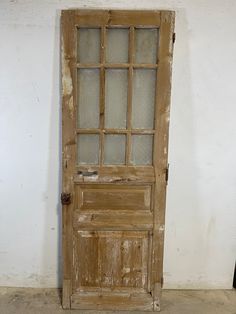 an old wooden door with glass panes on the top and bottom, in front of a white wall