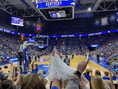 a crowd of people standing on top of a basketball court with blue and white uniforms