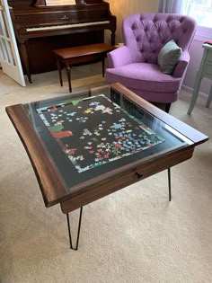 a living room with a piano, purple chair and glass top coffee table in it